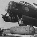 Preparing to bomb-up a Lancaster of No. 460 Squadron, armourer Cpl W. E. Dawson rides a 4,000lb high-capacity bomb (a 'Cookie'), while behind is a portion of the incendiary bomb containers which made up the normal load for area attacks, September 1943.