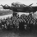 Squadron crews of mainly 'C' Flight lined up in front of 'A2' Aussie, March 1944. Vic Neale and crew, front right hand corner. In the background the station commanders, Group Captain, Hughie Edwards car or the car of the squadron commander, Wing Commander, H.D. Marsh.